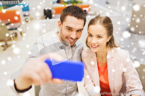 Image of happy couple taking selfie with smartphone in cafe