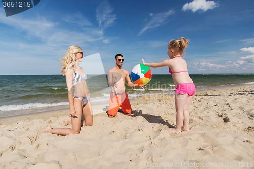 Image of happy family playing with inflatable ball on beach