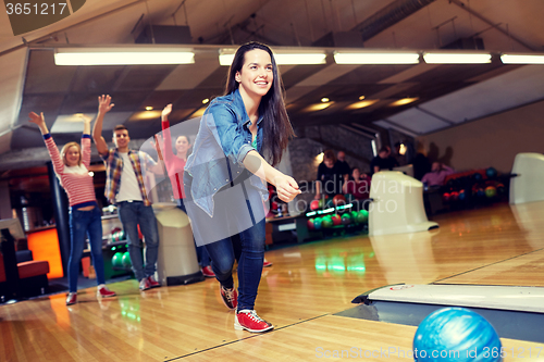 Image of happy young woman throwing ball in bowling club