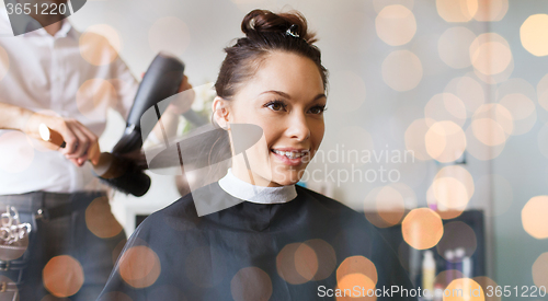 Image of happy woman with stylist making hairdo at salon