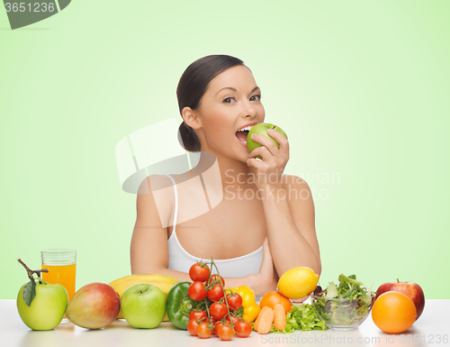 Image of woman with fruits and vegetables eating apple