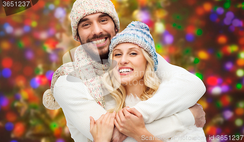 Image of happy couple in winter clothes hugging over lights