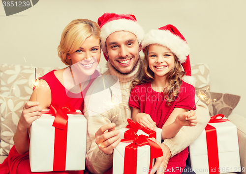 Image of smiling family holding gift boxes and sparkles