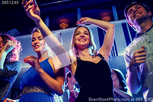 Image of smiling friends dancing in club