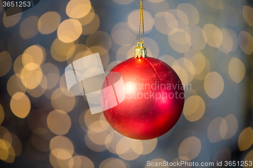 Image of close up of red christmas ball over golden lights