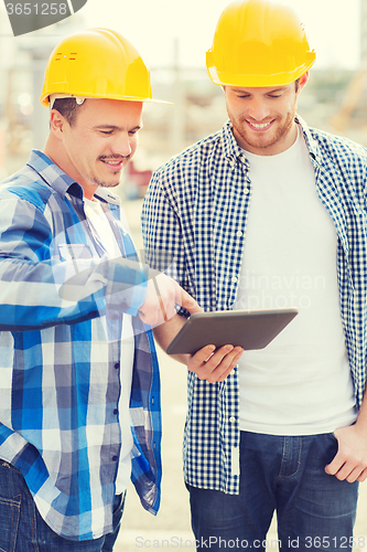 Image of smiling builders with tablet pc outdoors