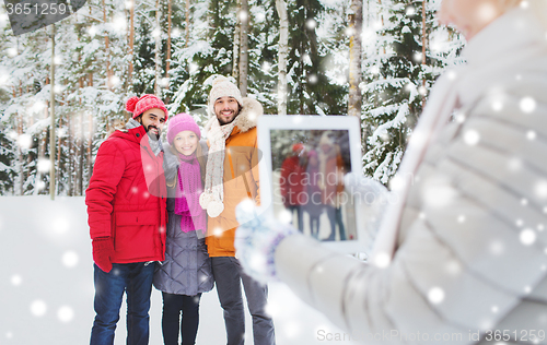 Image of smiling friends with tablet pc in winter forest