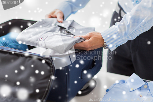 Image of businessman packing clothes into travel bag