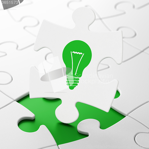 Image of Finance concept: Light Bulb on puzzle background