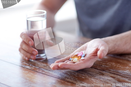 Image of close up of male hands holding pills and water