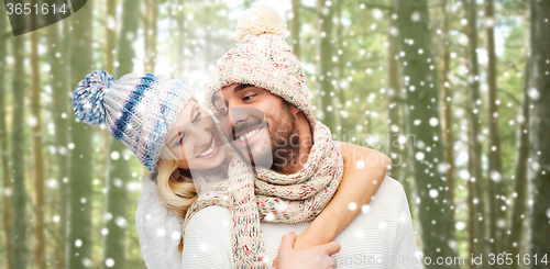 Image of happy couple in winter clothes hugging over forest