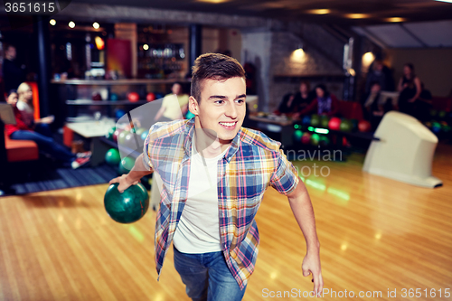 Image of happy young man throwing ball in bowling club