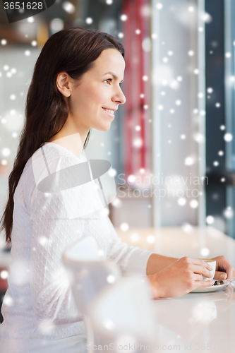 Image of smiling young woman drinking coffee at cafe