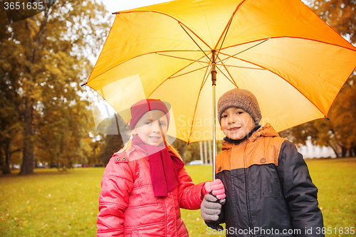 Image of happy boy and girl with umbrella in autumn park