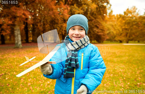 Image of happy little boy playing with toy plane outdoors