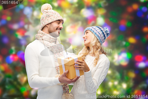 Image of smiling couple in winter clothes with gift box