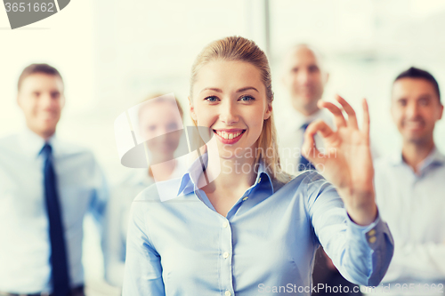 Image of smiling businesswoman showing ok sign in office