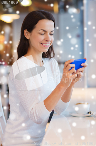 Image of smiling woman with smartphone and coffee at cafe