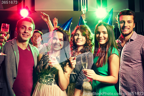 Image of smiling friends with glasses of champagne in club