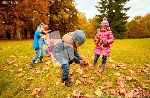 Image of group of children collecting leaves in autumn park