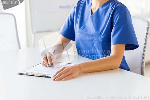 Image of close up of doctor or nurse writing to clipboard