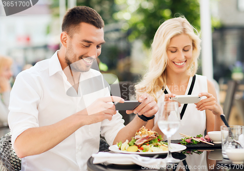 Image of happy couple with smatphone photographing food