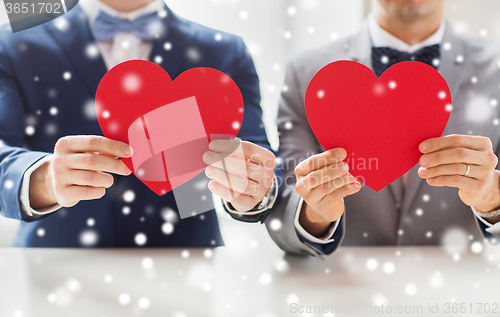 Image of close up of male gay couple holding red hearts