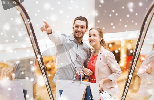 Image of couple with shopping bags on escalator in mall