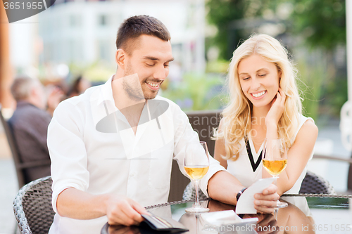 Image of happy couple with wallet and bill at restaurant