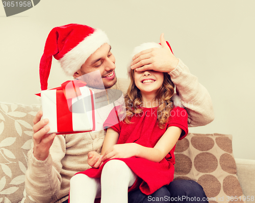 Image of smiling father surprises daughter with gift box