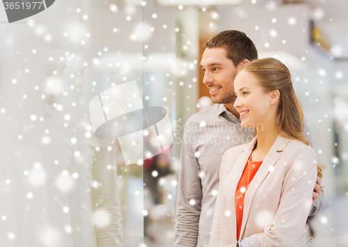 Image of happy couple looking to shop window in mall