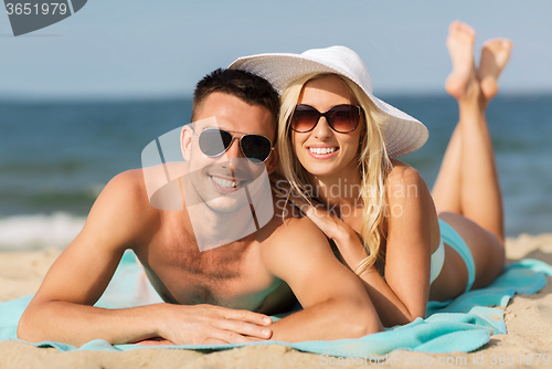 Image of happy couple in swimwear lying on summer beach