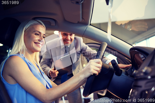 Image of happy woman with car dealer in auto show or salon