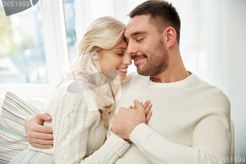 Image of happy couple covered with plaid on sofa at home