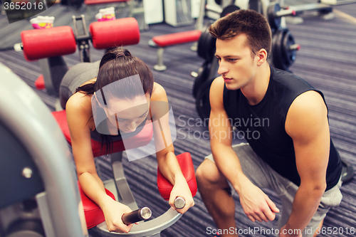 Image of young woman with trainer exercising on gym machine