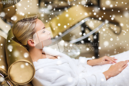 Image of beautiful young woman sitting in bath robe at spa