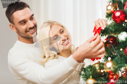Image of happy couple decorating christmas tree at home