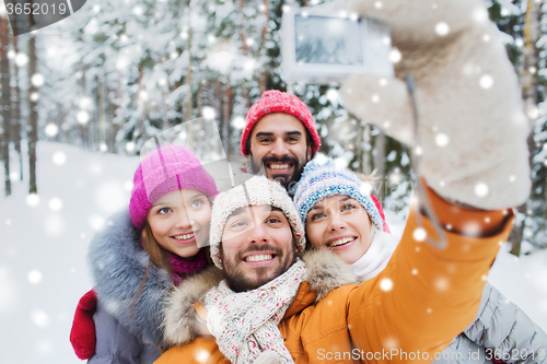 Image of smiling friends with camera in winter forest