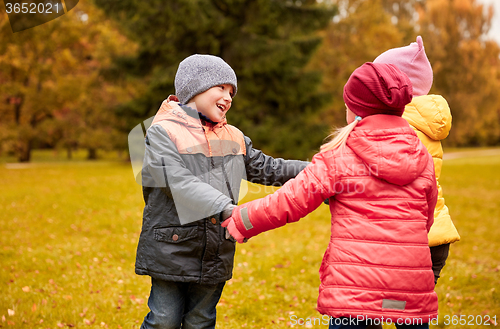 Image of children holding hands and playing in autumn park