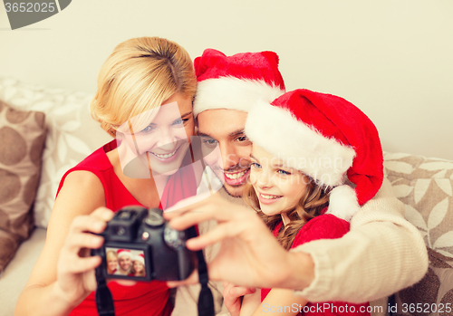 Image of smiling family in santa helper hats taking picture