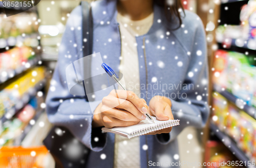 Image of close up of woman writing to notepad in market