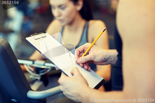 Image of close up of trainer hands with clipboard in gym