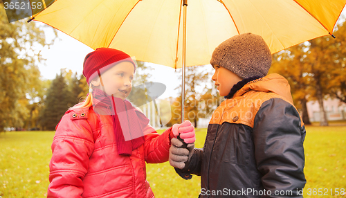 Image of happy boy and girl with umbrella in autumn park