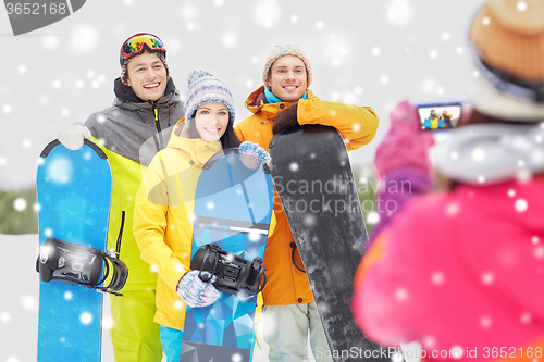 Image of happy friends with snowboards and smartphone