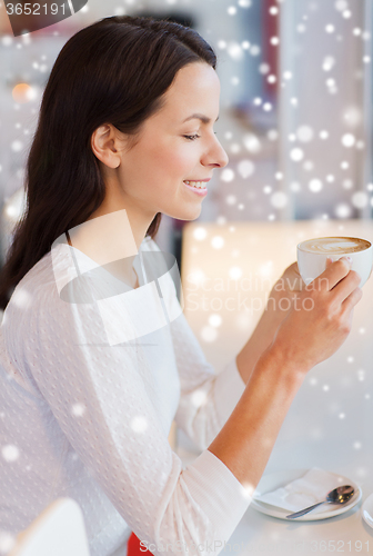 Image of smiling young woman drinking coffee at cafe