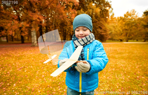 Image of happy little boy playing with toy plane outdoors