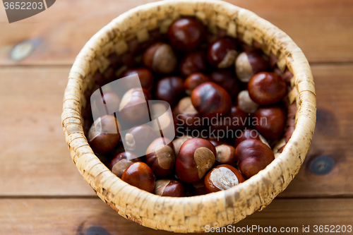 Image of close up of chestnuts in basket on wooden table