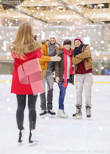 Image of happy friends taking photo on skating rink