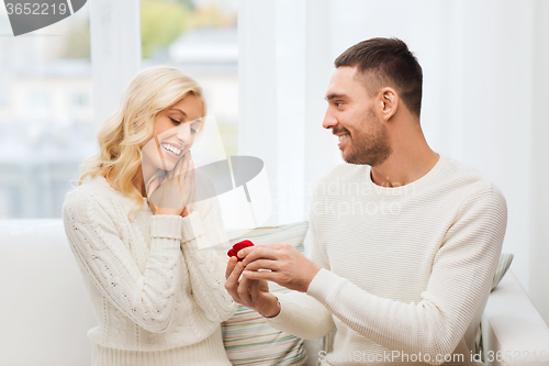 Image of happy man giving engagement ring to woman at home