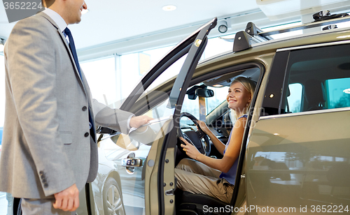 Image of happy woman with car dealer in auto show or salon